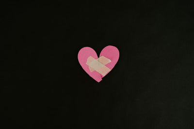 black background with a pink broken paper heart
