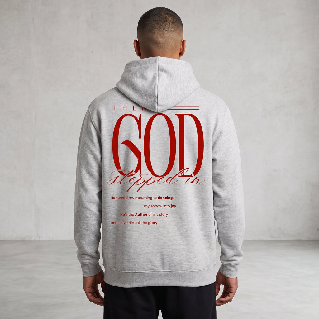 A man viewed from behind wearing a light gray hoodie with a large red graphic text print on the back reading 'GOD stepped in', set against a neutral gray textured wall.