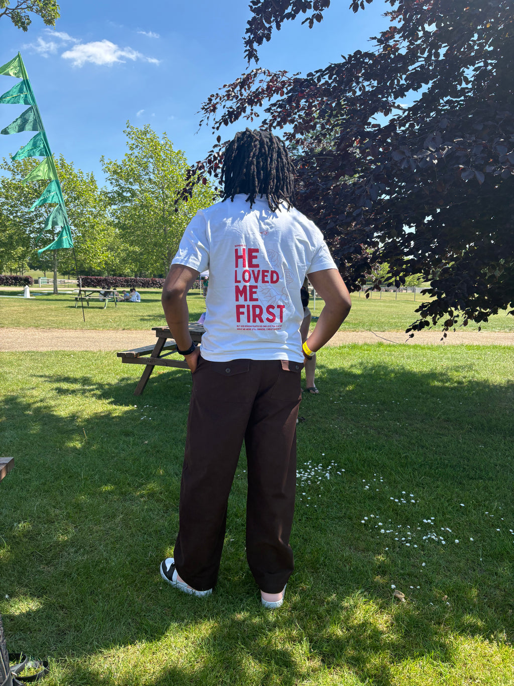 Person wearing a white t-shirt with text in a park
