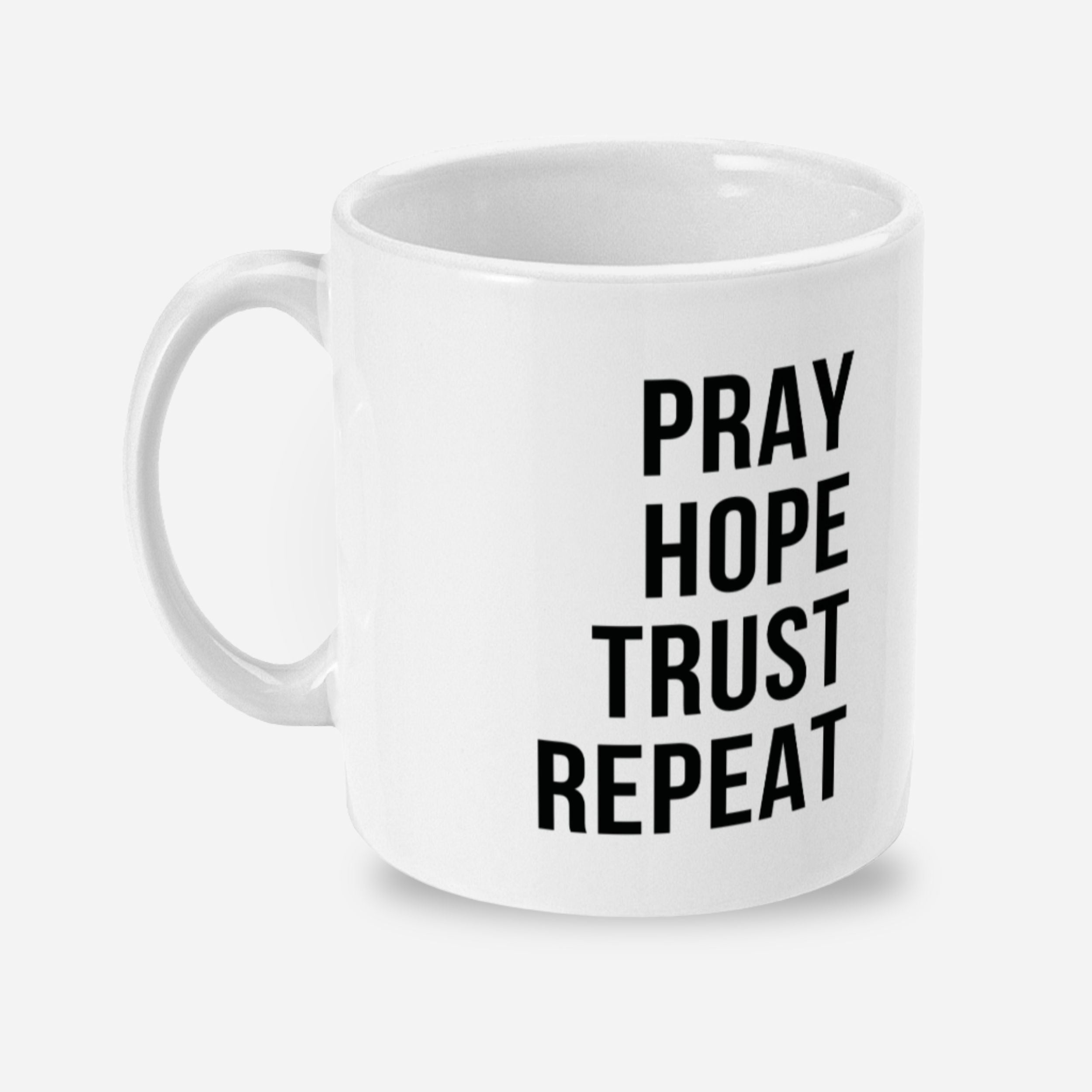 White mug with black text 'PRAY HOPE TRUST REPEAT' on a white background