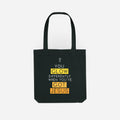 Black tote bag with yellow and white text on a white background you glow differently when you've got Jesus stay lit apparel tote bag